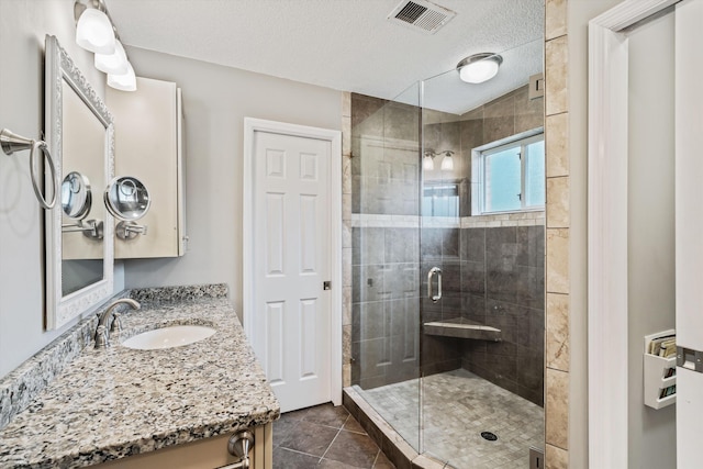 bathroom featuring vanity, an enclosed shower, a textured ceiling, and tile patterned flooring