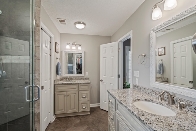 bathroom with vanity, tile patterned floors, a textured ceiling, and a shower with door