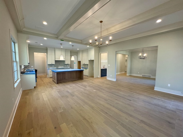 kitchen with pendant lighting, a large island, white cabinetry, and light hardwood / wood-style flooring