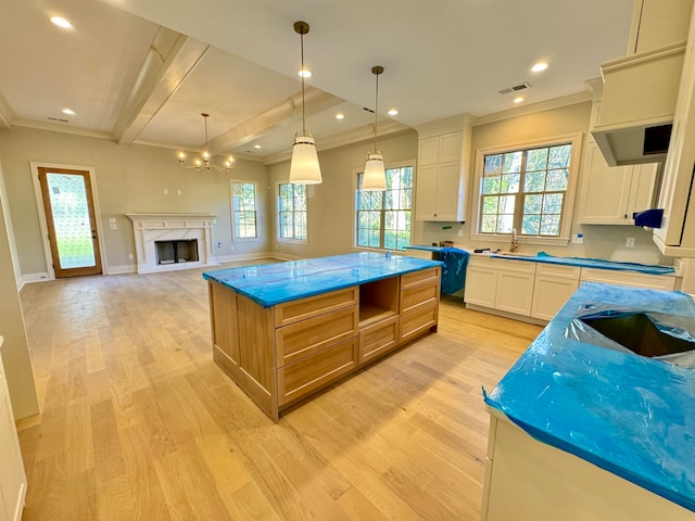 kitchen featuring white cabinets, light stone counters, hanging light fixtures, and a large island