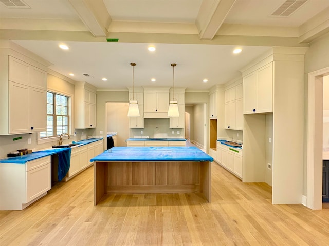 kitchen with beam ceiling, a center island, light hardwood / wood-style flooring, and pendant lighting