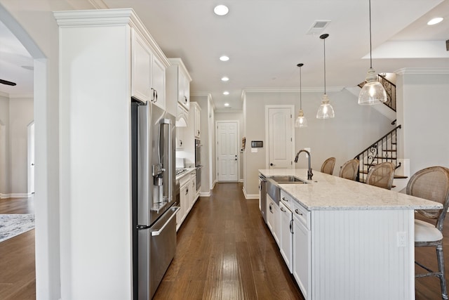 kitchen featuring a center island with sink, white cabinets, hanging light fixtures, and stainless steel appliances