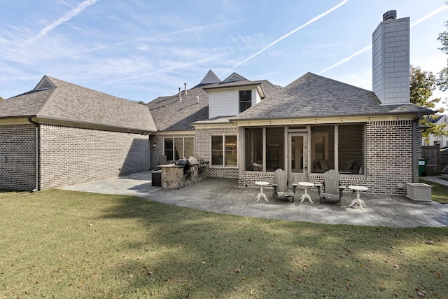 back of property with a sunroom, a patio area, and a lawn