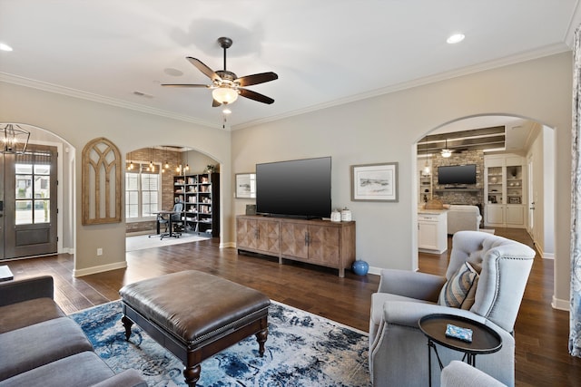 living room with crown molding, dark hardwood / wood-style floors, and ceiling fan with notable chandelier