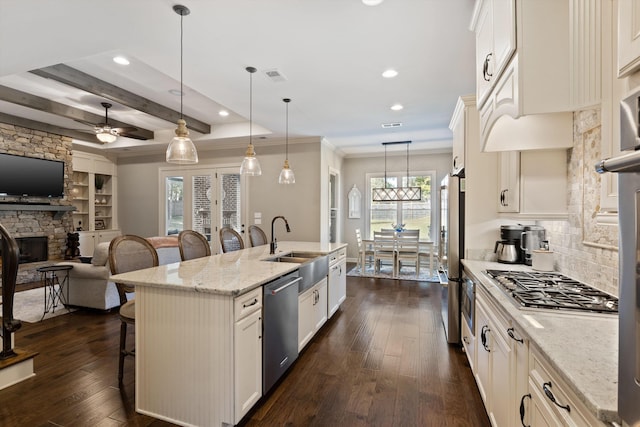 kitchen featuring a kitchen island with sink, a breakfast bar area, dark wood-type flooring, light stone countertops, and appliances with stainless steel finishes