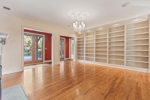 unfurnished living room featuring a notable chandelier, built in features, and wood-type flooring