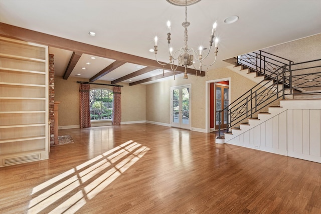 unfurnished living room featuring beam ceiling, a notable chandelier, and wood-type flooring