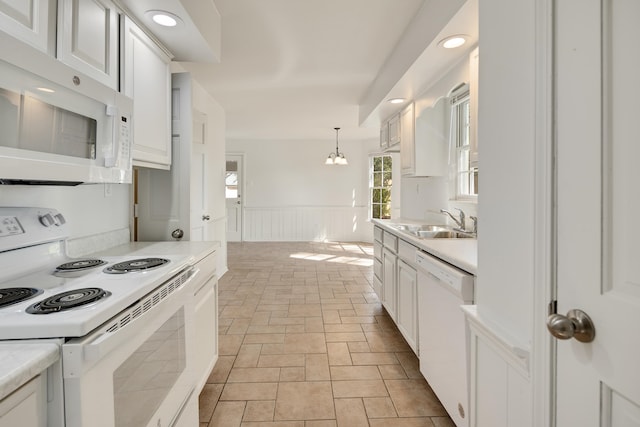 kitchen featuring white cabinets, white appliances, an inviting chandelier, and sink