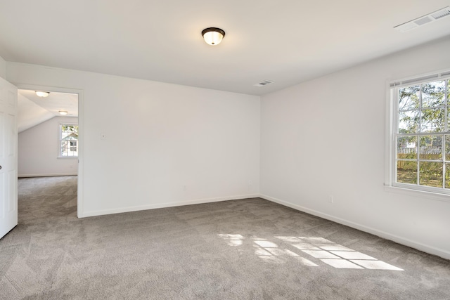 carpeted spare room with vaulted ceiling