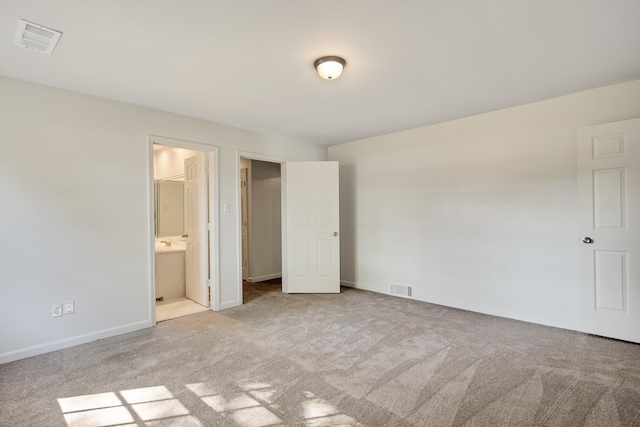 unfurnished bedroom with light carpet, connected bathroom, and a spacious closet