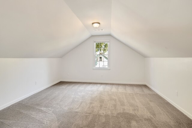 additional living space with light colored carpet and vaulted ceiling