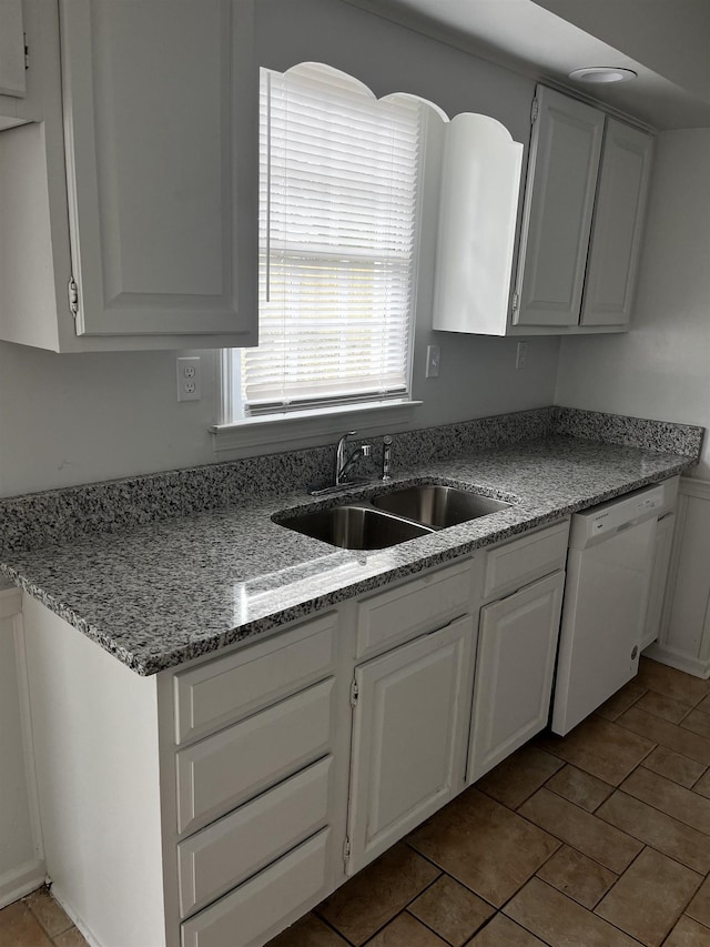 kitchen featuring white dishwasher, white cabinets, sink, light stone countertops, and light tile patterned flooring