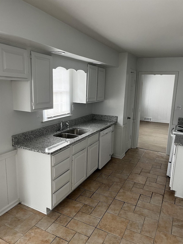 kitchen with white dishwasher, white cabinets, range, and sink