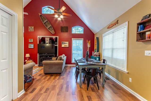 dining area with hardwood / wood-style floors, high vaulted ceiling, and ceiling fan