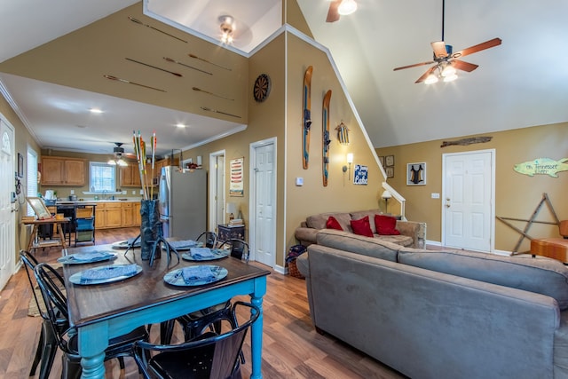 living room with ornamental molding, hardwood / wood-style floors, sink, and high vaulted ceiling