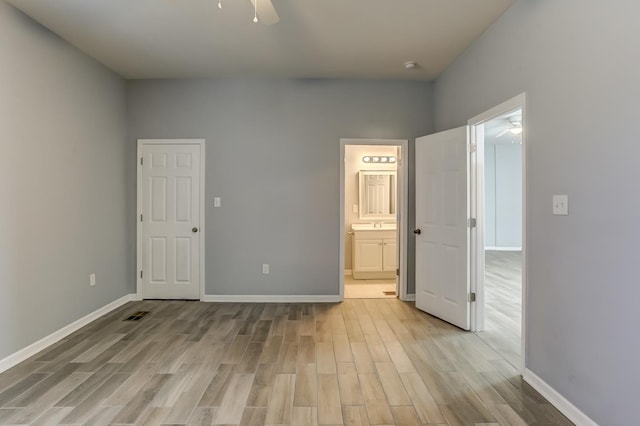 unfurnished bedroom with baseboards, visible vents, ensuite bathroom, and light wood finished floors