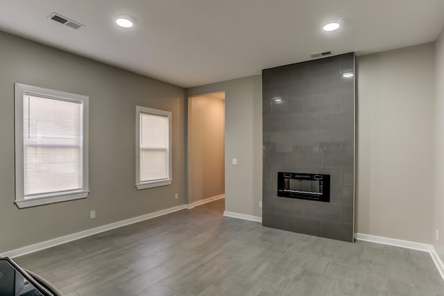 unfurnished living room with baseboards, recessed lighting, a tile fireplace, and visible vents
