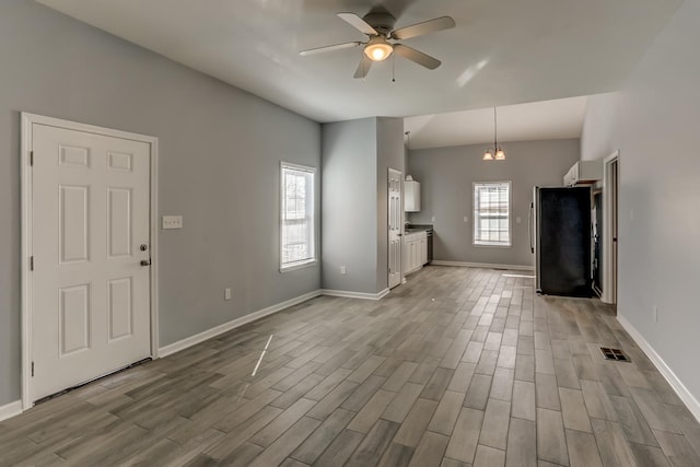 unfurnished living room with visible vents, wood finished floors, baseboards, ceiling fan, and vaulted ceiling