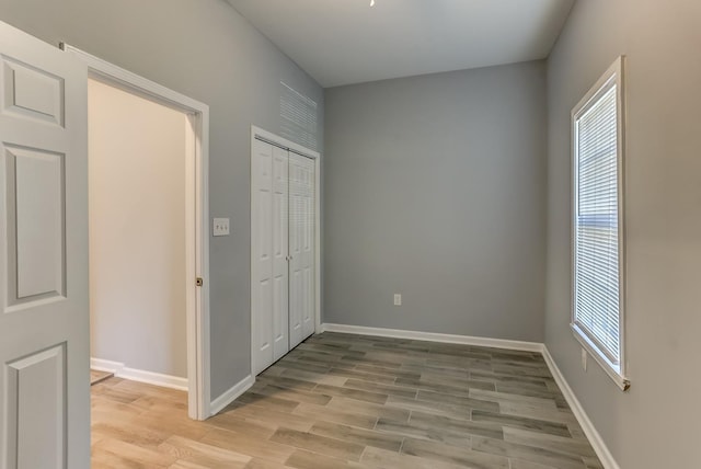 unfurnished bedroom with a closet, baseboards, and light wood-style floors
