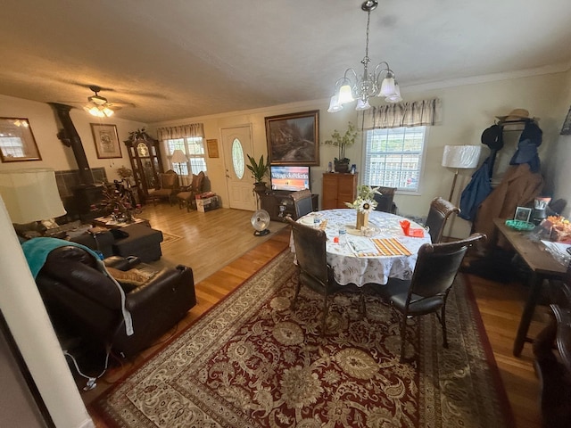 dining room featuring ceiling fan with notable chandelier, crown molding, a wood stove, and dark hardwood / wood-style floors