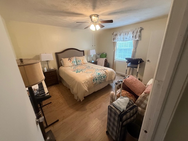 bedroom featuring a textured ceiling, light wood-type flooring, and ceiling fan