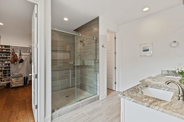 bathroom featuring a shower with door and vanity