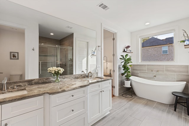 full bathroom featuring vanity, toilet, tile walls, and separate shower and tub