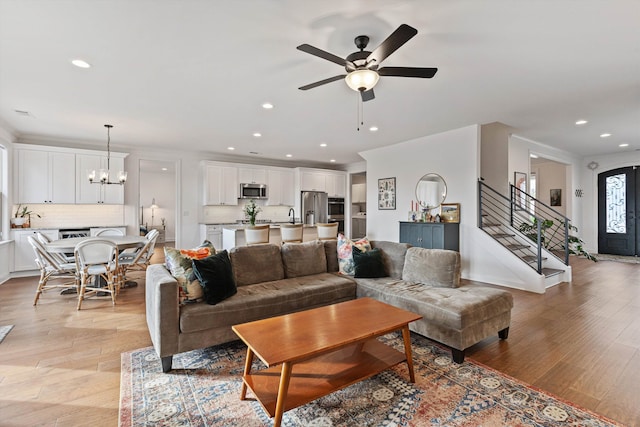 living room with light hardwood / wood-style floors, sink, and ceiling fan with notable chandelier