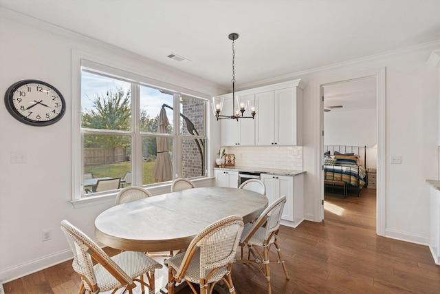 dining space featuring an inviting chandelier, ornamental molding, and dark wood-type flooring