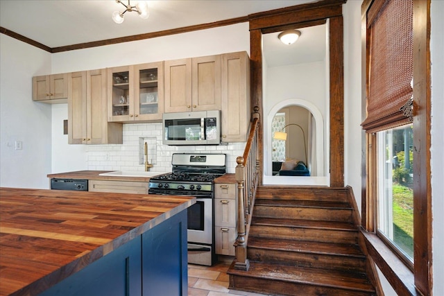 kitchen with wooden counters, light brown cabinets, stainless steel appliances, crown molding, and tasteful backsplash