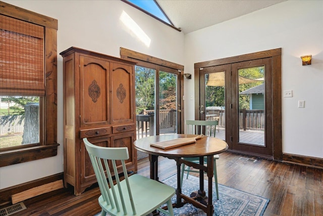 dining area with french doors, vaulted ceiling, a healthy amount of sunlight, and dark hardwood / wood-style flooring