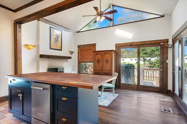 kitchen featuring ceiling fan, blue cabinetry, dark wood-type flooring, crown molding, and butcher block countertops