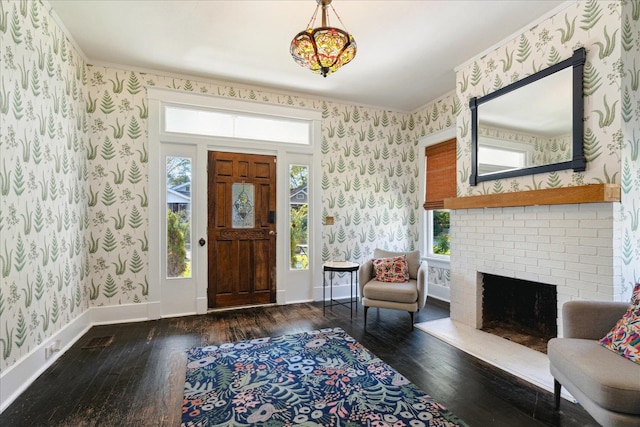 foyer entrance with a brick fireplace, dark hardwood / wood-style floors, and a healthy amount of sunlight