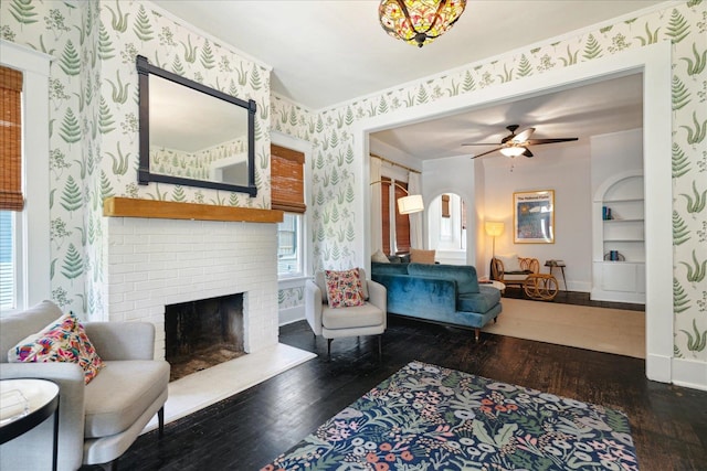 living room with ceiling fan, built in features, dark hardwood / wood-style flooring, and a fireplace