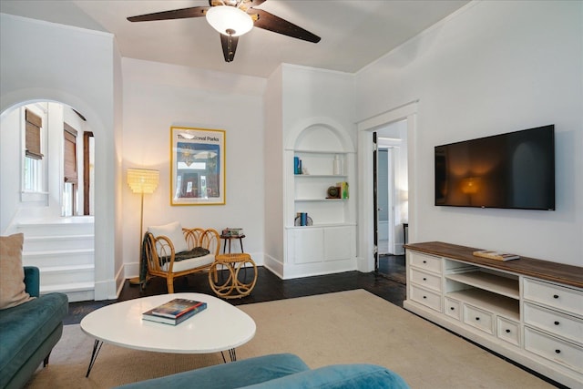 living room with dark hardwood / wood-style floors, built in shelves, and ceiling fan