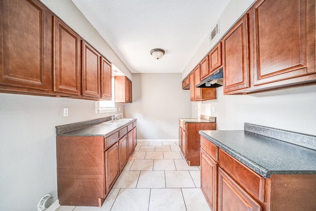 kitchen featuring a textured ceiling, sink, and light tile patterned floors