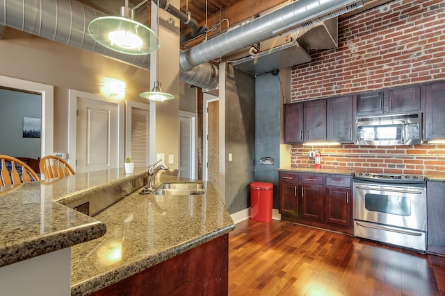 kitchen with sink, stone countertops, dark wood-type flooring, and stainless steel appliances