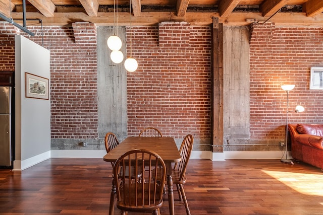 unfurnished dining area with dark hardwood / wood-style floors, beam ceiling, and brick wall