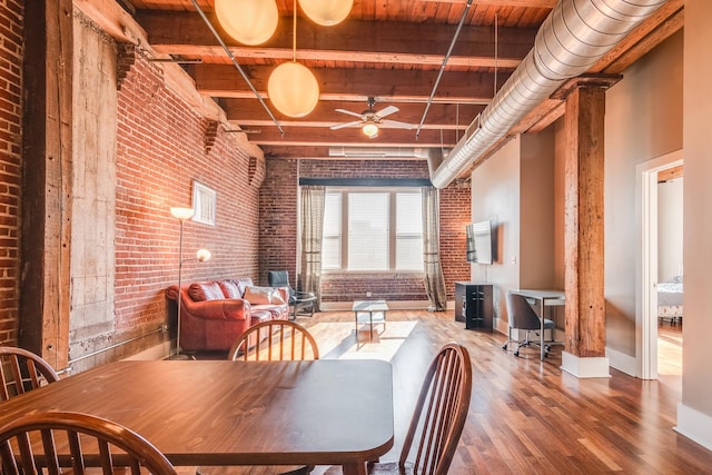 dining room with wood-type flooring, wooden ceiling, a high ceiling, beam ceiling, and brick wall