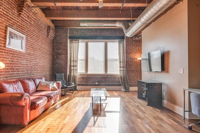 living room featuring wood ceiling, wood-type flooring, beamed ceiling, a high ceiling, and brick wall