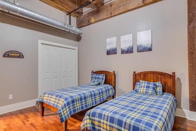 bedroom with a closet, beam ceiling, and hardwood / wood-style flooring