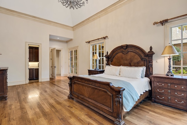 bedroom with connected bathroom, a high ceiling, crown molding, and light hardwood / wood-style floors