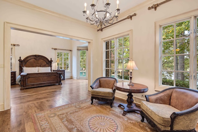 sitting room featuring ornamental molding, hardwood / wood-style floors, a notable chandelier, and plenty of natural light