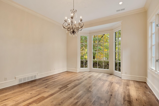 unfurnished dining area with crown molding, a wealth of natural light, light wood-type flooring, and an inviting chandelier