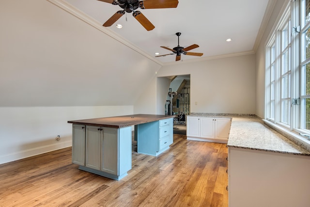 kitchen featuring white cabinets, ceiling fan, ornamental molding, light hardwood / wood-style floors, and a center island