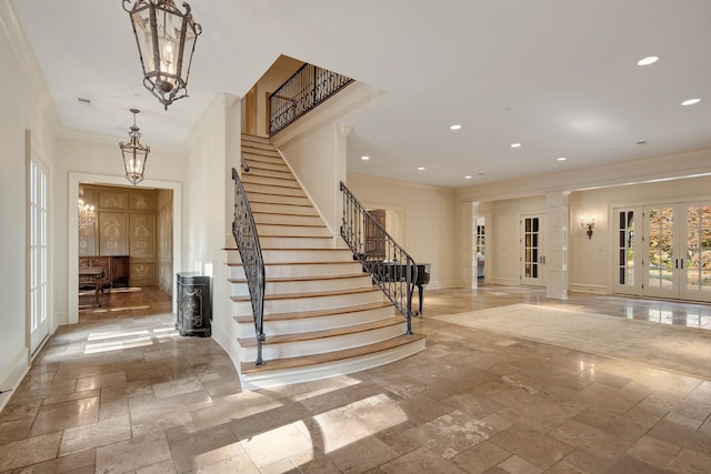 entrance foyer with french doors, ornamental molding, and decorative columns