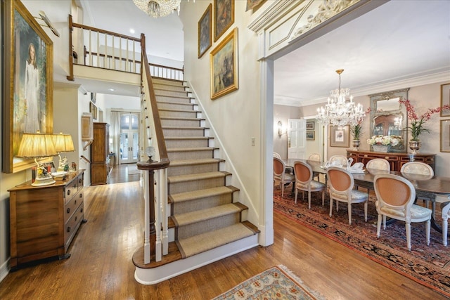 stairs with hardwood / wood-style flooring, ornamental molding, and a chandelier