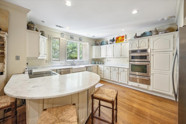 kitchen with appliances with stainless steel finishes, a breakfast bar, kitchen peninsula, and white cabinets