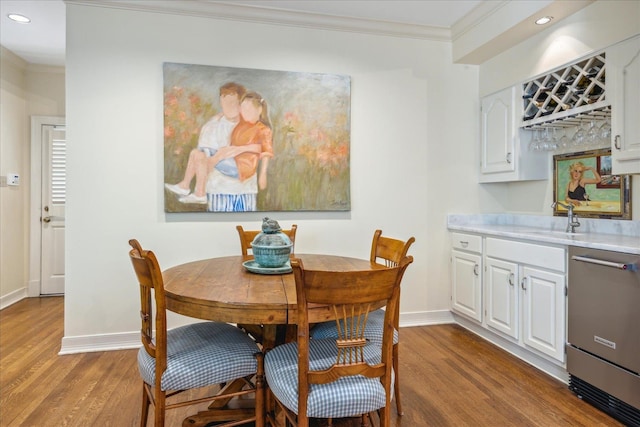 dining space with wet bar, wood-type flooring, and ornamental molding