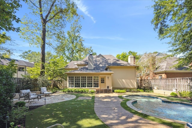 rear view of property with a yard, a patio area, a fenced in pool, and a sunroom